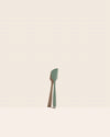 The GIR Sage Green Mini Spatula on a pink background.