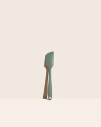 The GIR Sage Green Ultimate Spatula on a pink background.